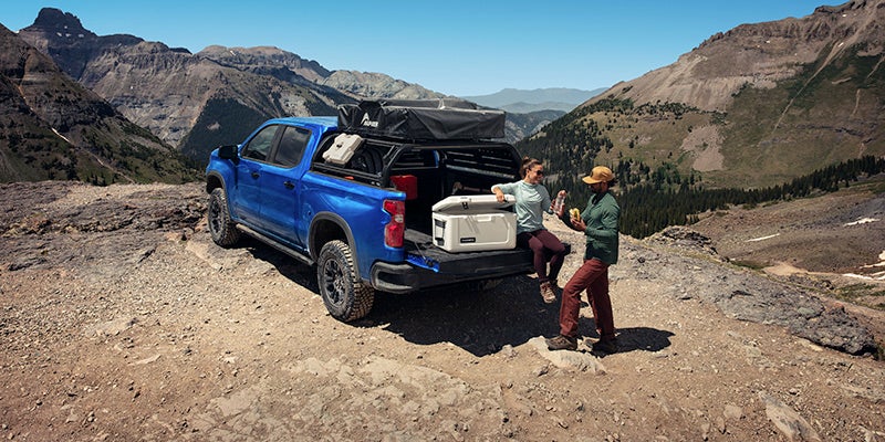 Two people with a cooler on the open tailgate of a Silverado