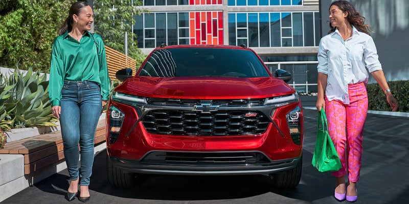 Two women outside a red 2025 Chevy Trax